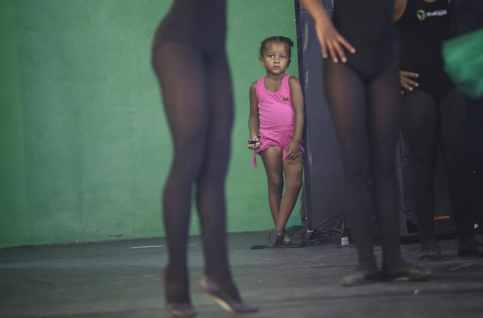 A girl watches dancers perform before members of London's Royal Opera House in the Vigario Geral slum of Rio de Janeiro, Brazil, Saturday, March 2, 2013. This past week Royal Ballet dancers shared their knowledge and advice with promising artists during an education symposium between the company and the cultural arts center Afro Reggae. (AP Photo/Silvia Izquierdo)