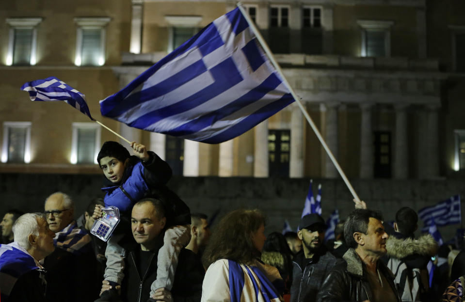 Opponents of Prespa Agreement, holding Greek flags, participate in a rally outside the Greek Parliament, background, in Athens, Thursday, Jan. 24, 2019. Greek lawmakers are debating a historic agreement aimed at normalising relations with Macedonia in a stormy parliamentary session scheduled to culminate in a Friday vote. (AP Photo/Thanassis Stavrakis)