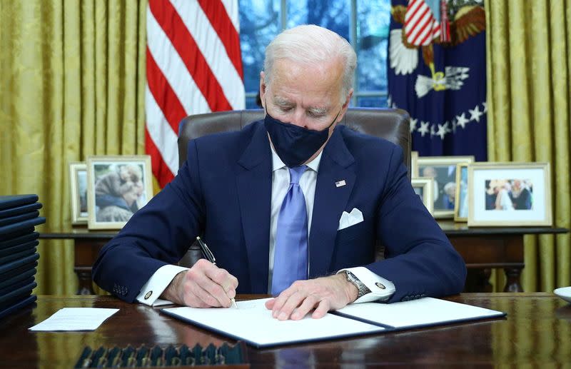President Joe Biden signs executive orders inside the Oval Office at the White House in Washington