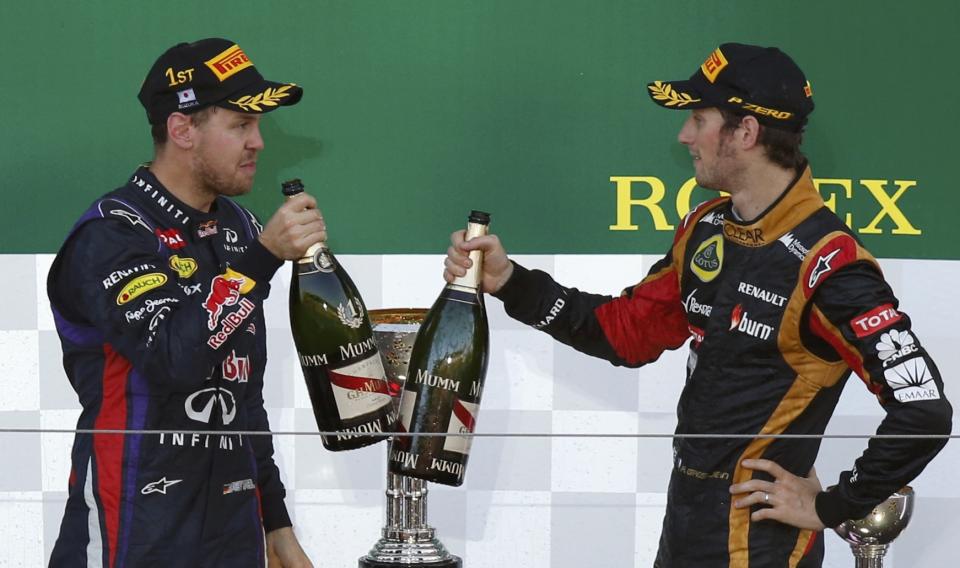 Red Bull Formula One driver Sebastian Vettel (L) of Germany toasts third-placed Lotus Formula One driver Romain Grosjean of France on the podium after winning the Japanese F1 Grand Prix at the Suzuka circuit October 13, 2013. REUTERS/Toru Hanai (JAPAN - Tags: SPORT MOTORSPORT F1)