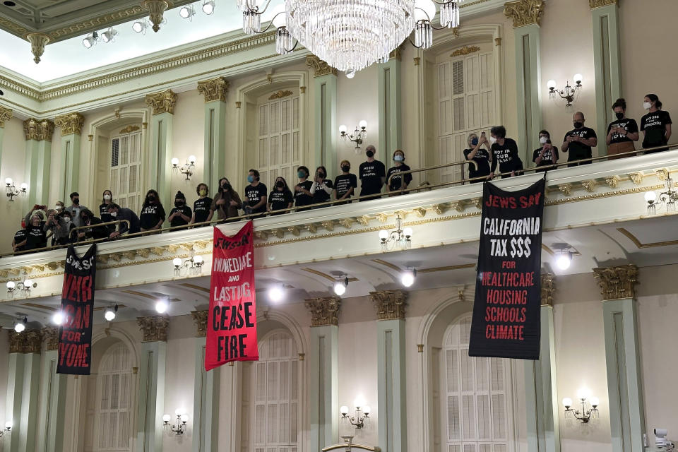 Protesters calling for a cease-fire in the Israel-Hamas war stand and sing in the Assembly chamber of the State Capitol in Sacramento, Calif., Wednesday, Jan. 3, 2024. The Assembly adjourned shortly after the protest began. (AP Photo/Adam Beam)