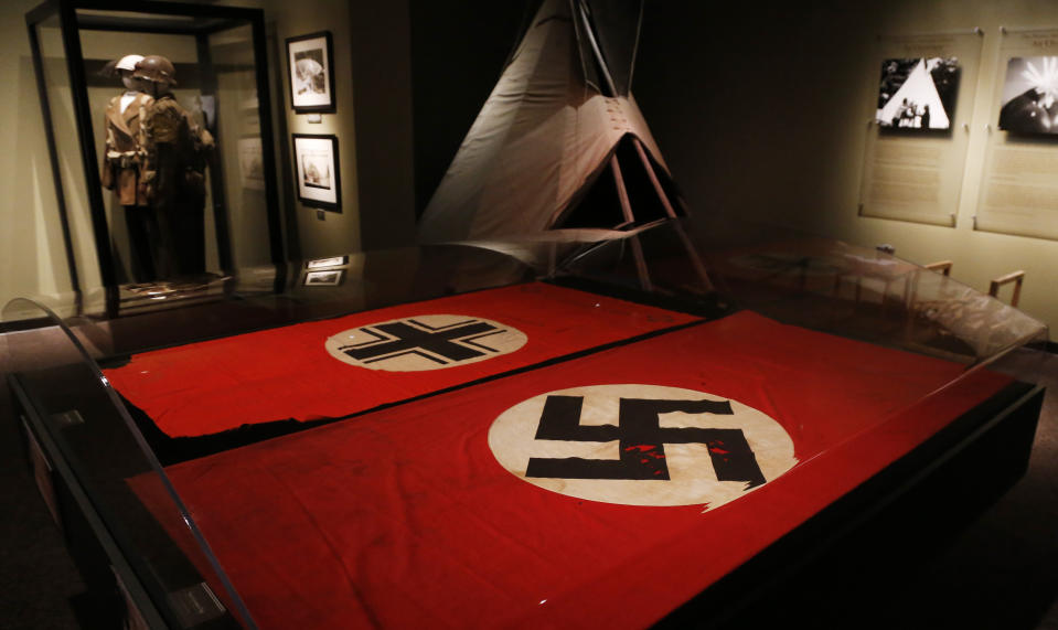 Two flags are on display in an exhibit about the Comanche Code Talkers at the Comanche National Museum & Cultural Center in Lawton, Okla, Thursday, Sept. 26, 2013. At left is the Baltic Cross captured by Comanche Code Talker Larry Saupitty, at right is a Nazi German flag with the swastika captured by Code Talker Charles Chibitty. (AP Photo/Sue Ogrocki)