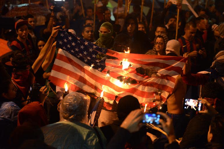 Young demonstrators burn a US flag during a march of thousands toward the US Embassy demanding the resignation of Honduras President Juan Orlando Hernandez, accused of corruption, in Tegucigalpa, June 12, 2015