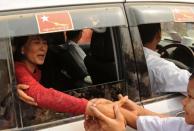 Myanmar opposition leader Aung San Suu Kyi greets supporters as she travels through the constituency where she is standing as a candidate in Kawhmu on April 1, 2012