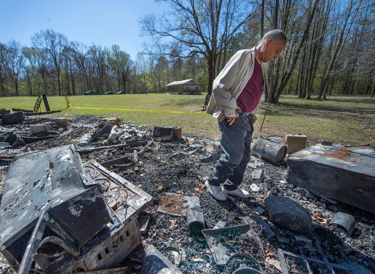 Floyd Bailey, curator of the Mississippi John Hurt landmarks, walks through the charred and melted remains of the John Hurt Museum in Carroll County on Friday. Bailey describes what the building looked like before the Feb. 21 fire burned the museum to the ground. In the background is St. James Missionary Baptist Church, where John Hurt's funeral was held.