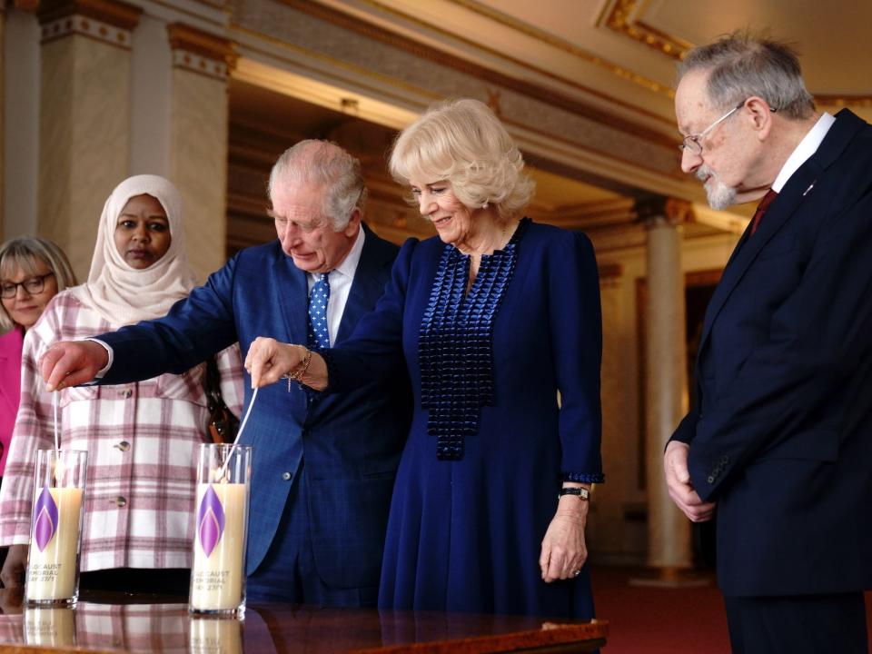 King Charles III and Camilla, Queen Consort light a candle at Buckingham Palace to mark Holocaust Memorial Day alongside Holocaust survivor Dr Martin Stern and a survivor of the Darfur genocide, Amouna Adam on January 27, 2023.