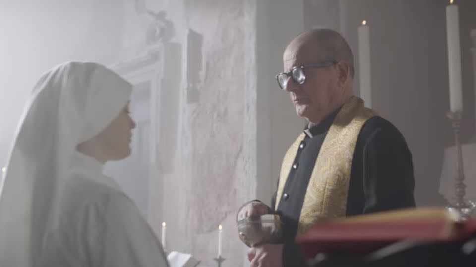A nun about to receive a potato chip from a priest in the commercial. - Amica Chips/Instagram