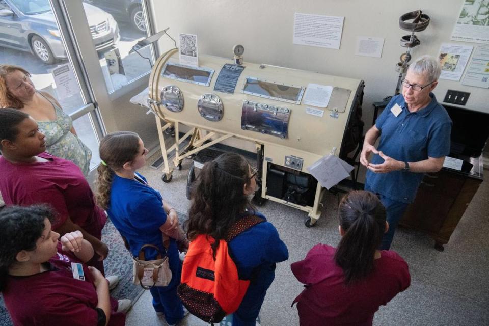 Dr. John Vallee, a retired OB-GYN, shows a tour group of UEI College students an iron lung at the Museum of Medical History in East Sacramento on Thursday. Vallee said the medical respirator could help a polio patient breathe by creating a vacuum around the patient’s body.