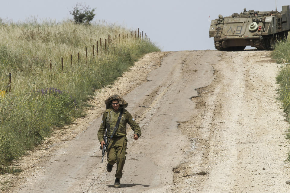 <p>An Israeli soldier runs to direct a M113 armored personal vehicle near the Syrian border in the Israel-annexed Golan Heights on May 10, 2018. Israel’s army said today it had carried out widespread raids against Iranian targets in Syria overnight after rocket fire towards its forces it blamed on Iran, marking a sharp escalation between the two enemies. Israel carried out the raids after it said around 20 rockets, either Fajr or Grad type, were fired from Syria at its forces in the occupied Golan Heights at around midnight. (Photo: Jalaa Marey/AFP/Getty Images) </p>