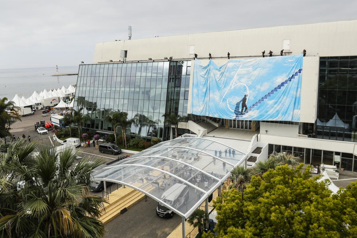 Festival workers pull the official poster into place at the Grand Theatre Lumiere during preparations for the 75th international film festival, Cannes, southern France, Sunday, May 15, 2022. The Cannes film festival runs from May 17th until May 28th 2022. (AP Photo/Dejan Jankovic)