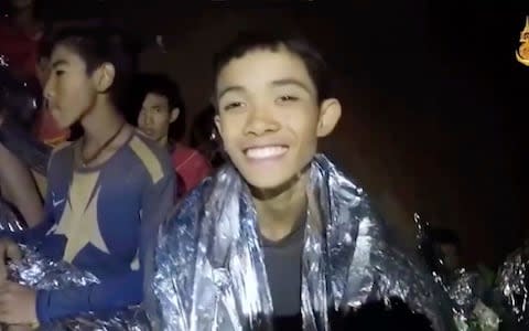 A Thai boy smiles as Thai Navy SEAL medics help injured children inside the cave in Mae Sai, northern Thailand - Credit: Royal Thai Navy Facebook Page