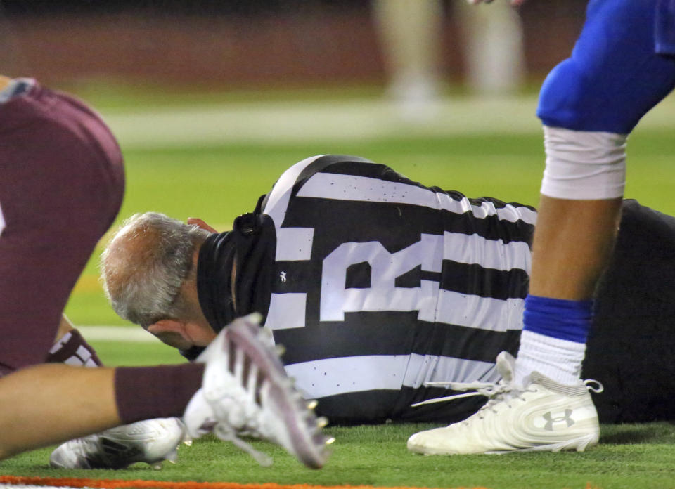 Football referee Fred Gracia lies on the ground rafter being charged by Edinburg's Emmanuel Duron in a high school zone play-in game between Edinburg and Pharr-San Juan-Alamo on Thursday, Dec. 3, 2020, in Edinburg, Texas. (Joel Martinez/The Monitor via AP)