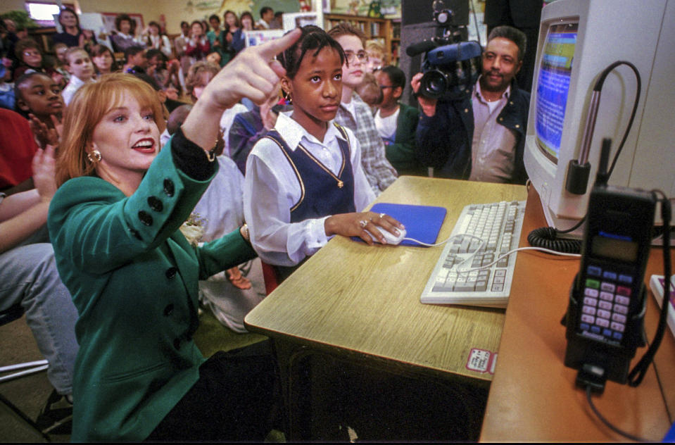 FILE - Shawntel Smith Wuerch, left, Miss America 1996, shows the organization's homepage with help from student Quinesha Farr, 11, during a visit to showcase advance internet technology at Fuller Elementary School in Little Rock, Ark., Feb. 8, 1996. A donation from Smith Wuerch and her husband made it possible to award a top scholarship of $100,000 to this year's winner of the Miss America crown, marking 100 years of the competition, on Thursday, Dec. 16, 2021. (AP Photo/Spencer Tirey, File)