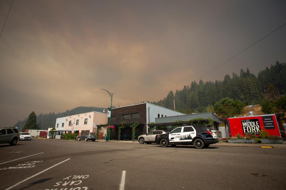 A police car drives through downtown Oakridge Friday, Sept. 9, 2022, as smoke from the Cedar Creek Fire hangs over town. 