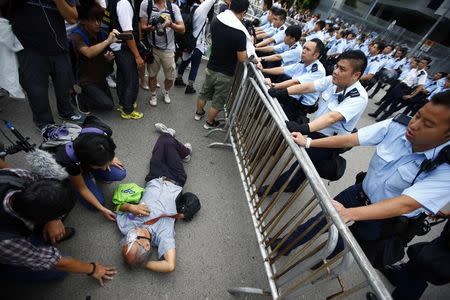 Police officers try to remove a protester from the entrance to Hong Kong's Chief Executive Leung Chun-ying offices next to the government headquarters building in Hong Kong, October 2, 2014. REUTERS/Carlos Barria