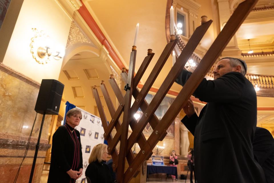 Shaul Jolles, left, helps Gov. Laura Kelly lights the menorah inside the Statehouse during Tuesday's Chanukah at the Capitol Community Celebration.