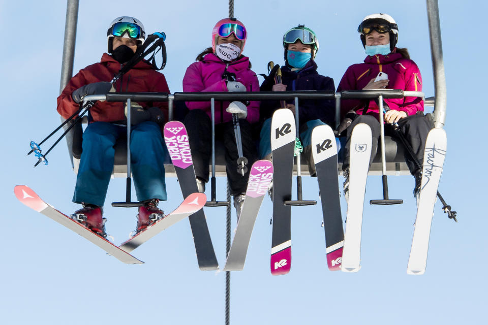 FILE - In this Oct. 30, 2020 file photo skiers wearing face masks riding a chairlift on the opening day of the Verbier ski area in the Swiss Alps, EU member states Austria, France, Germany and Italy are shutting or severely restricting access to the slopes this holiday season amid COVID-19 concerns, Switzerland is not. (Jean-Christophe Bott/Keystone via AP, File)