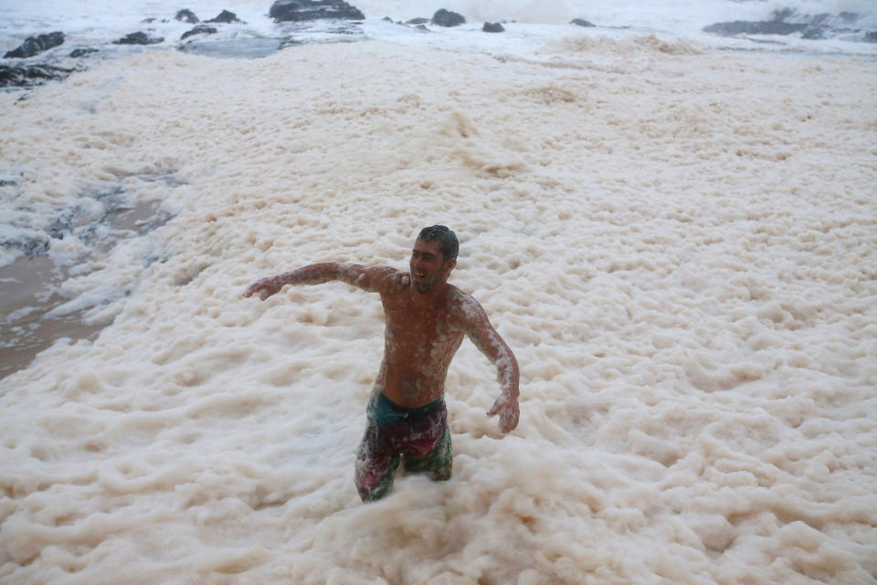 A man walks through ocean foam in Snapper Rocks as Queensland experiences severe rains and flooding from Tropical Cyclone Oswald on January 28, 2013 in Gold Coast, Australia. Hundreds have been evacuated from the towns of Gladstone and Bunderberg while the rest of Queensland braces for more flooding. (Photo by Chris Hyde/Getty Images)