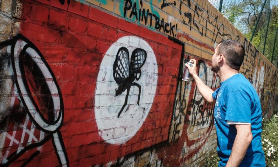 Street artist Ibo Omari paints over a swastika in Berlin.