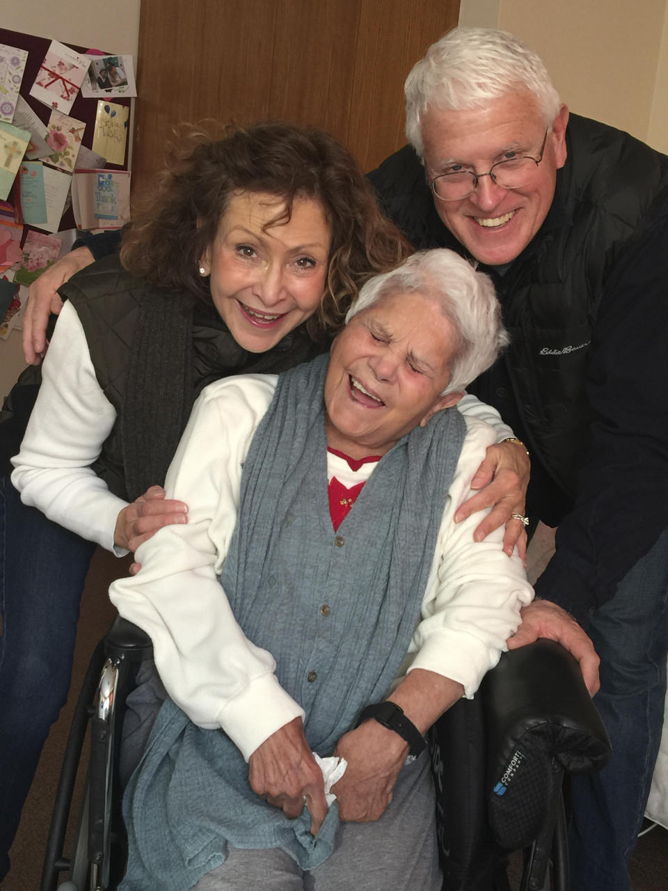 This Dec. 2017 photo provided by Julie Griffith shows Julie Griffith, left, with her mother Mabel Porter, center, and Griffith's husband, David, as they pose for a photo at a nursing home in Oregon, Ohio. The Griffiths are among those advocating to allow cameras inside long-term care facilities. Visitation bans at nursing homes because of the coronavirus have sparked renewed interest in legislation to allow the cameras.(Julie Griffith/Julie Griffith via AP)