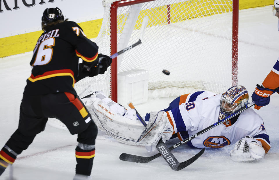 New York Islanders goalie Ilya Sorokin, right, lets in a goal by Calgary Flames forward Martin Pospisil, left, during first-period NHL hockey game action in Calgary, Alberta, Saturday, Nov. 18, 2023. (Jeff McIntosh/The Canadian Press via AP)