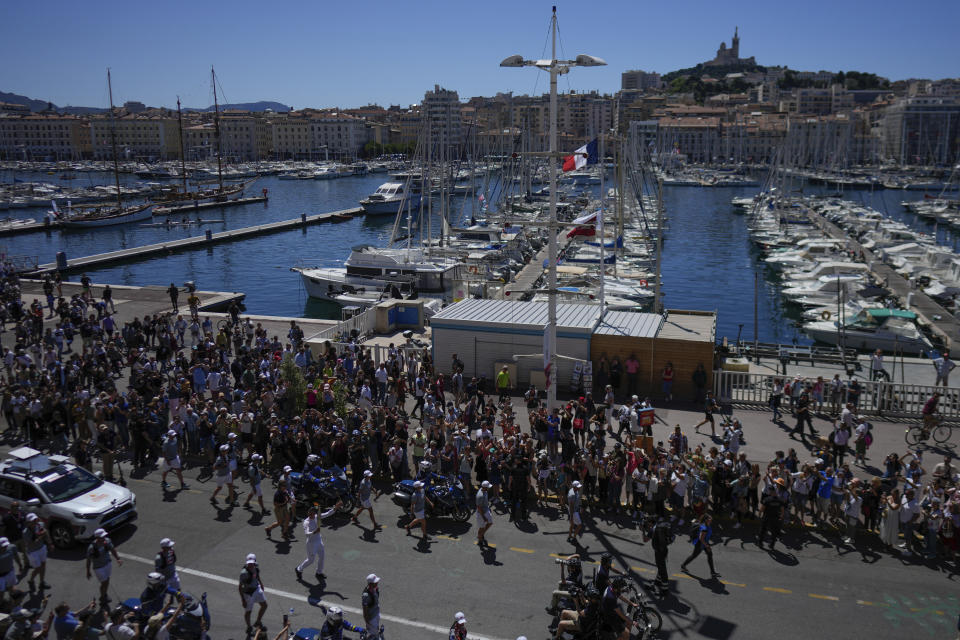 A torchbearer, bottom centre left, participates in the first stage of the Olympic torch relay in Marseille, southern France, Thursday, May 9, 2024. Torchbearers are to carry the Olympic flame through the streets of France' s southern port city of Marseille, one day after it arrived on a majestic three-mast ship for the welcoming ceremony. (AP Photo/Thibault Camus)