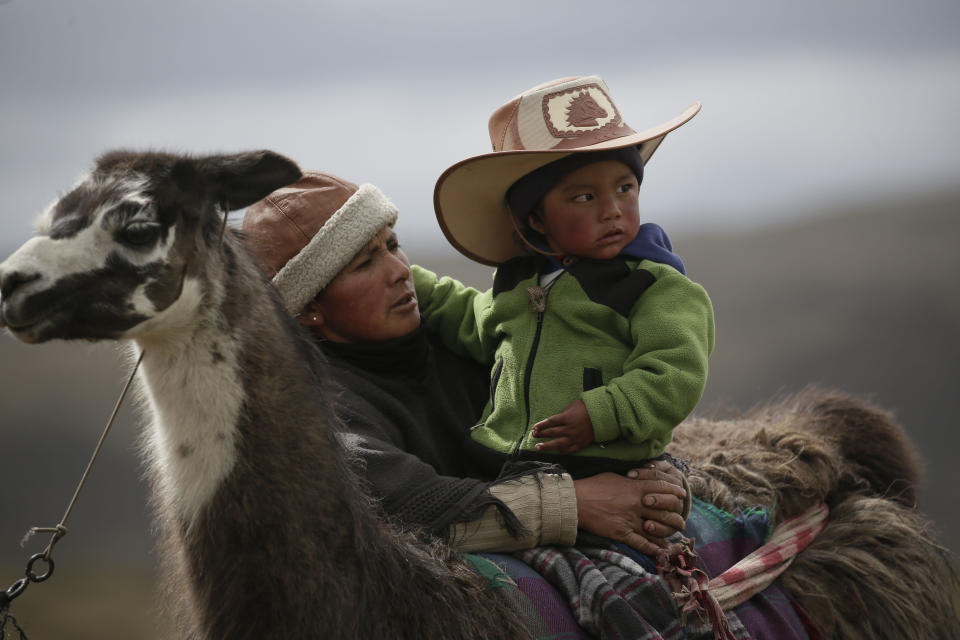A woman embraces her son during Llama races at the Llanganates National Park, Ecuador, Saturday, Feb. 8, 2020. Wooly llamas, an animal emblematic of the Andean mountains in South America, become the star for a day each year when Ecuadoreans dress up their prized animals for children to ride them in 500-meter races. (AP Photo/Dolores Ochoa)