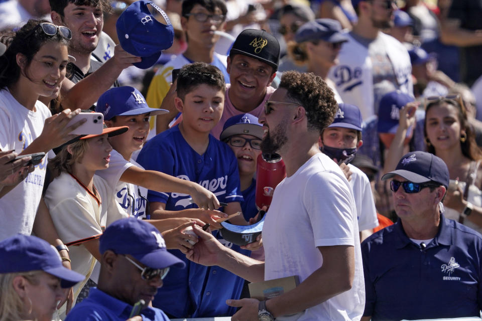 Klay Thompson of the Golden State Warriors signs autographs for fans while watching a baseball game between the Los Angeles Dodgers and the San Francisco Giants Sunday, July 24, 2022, in Los Angeles. Thompson is the brother of Los Angeles Dodgers' Trayce Thompson. (AP Photo/Mark J. Terrill)