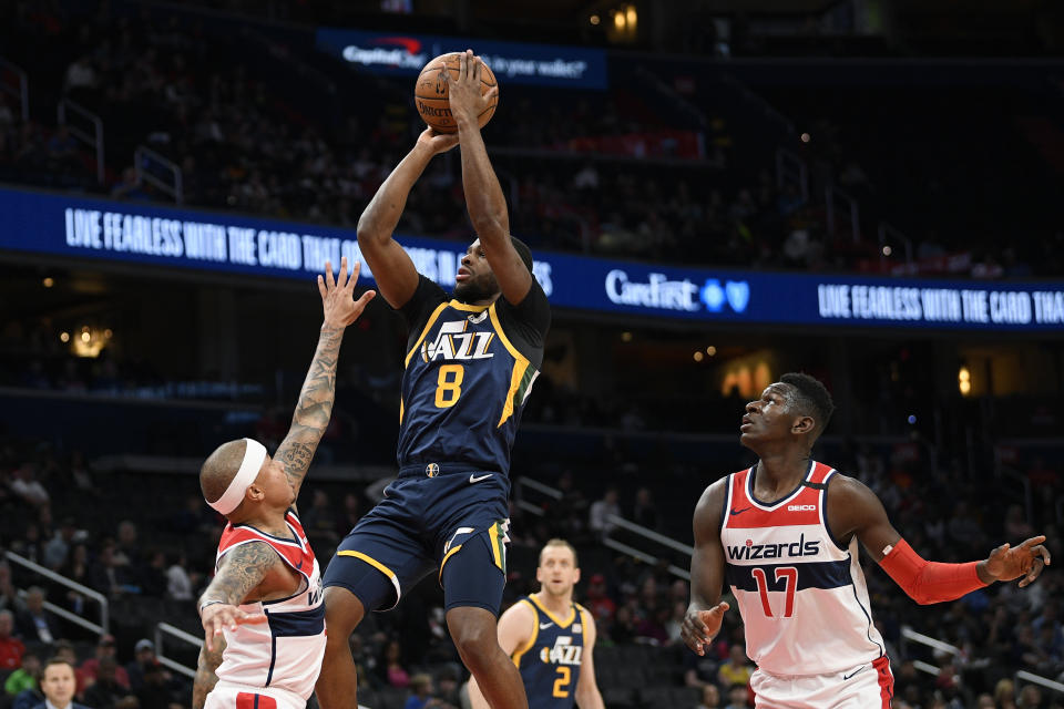 Utah Jazz guard Emmanuel Mudiay (8) shoots between Washington Wizards guards Isaiah Thomas, left, and Isaac Bonga (17) during the first half of an NBA basketball game, Sunday, Jan. 12, 2020, in Washington. (AP Photo/Nick Wass)