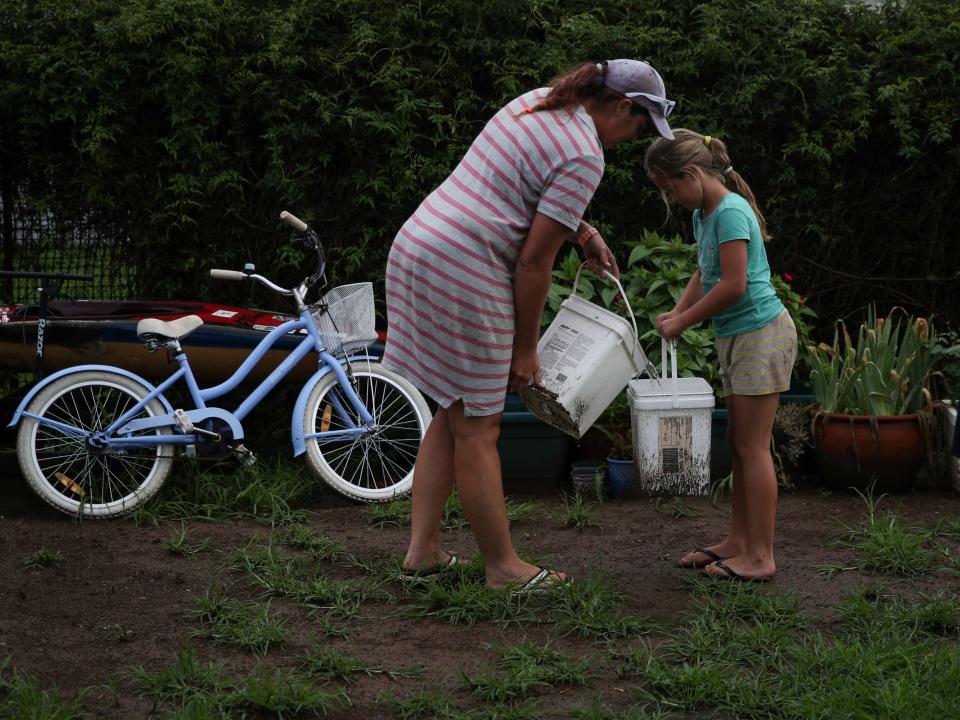 Eight-year-old Chelsea Symonds helps her mother Sally Roser to water plants in their yard with buckets of collected rainwater in the drought-affected town of Murrurundi, New South Wales, Australia February 17, 2020.   REUTERS/Loren Elliott