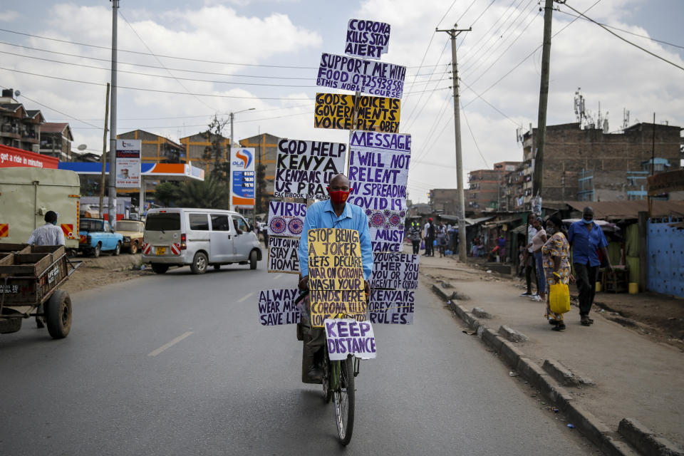 FILE - In this Thursday, May 28, 2020 file photo, Samson Waithaka rides a bicycle with informational messages warning about the new coronavirus in the Mathare slum, or informal settlement, of Nairobi, Kenya. A dangerous stigma has sprung up around the coronavirus in Africa — fueled, in part, by severe quarantine rules in some countries as well as insufficient information about the virus. (AP Photo/Brian Inganga, File)