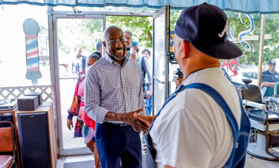 Democratic Senator from Georgia Raphael Warnock meets barber shop owner Stan Seldon  during a reelection campaign stop in Newnan, Georgia.