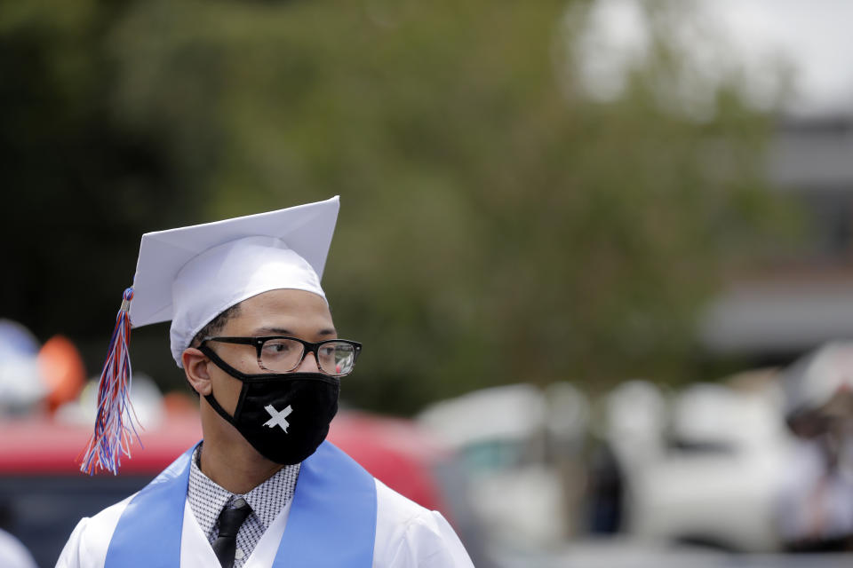 Jeremiah Fred wears a mask while he is waiting to receive his diploma as the New Orleans Charter Science and Math High School class of 2020 holds a drive-in graduation ceremony as a result of the COVID-19 pandemic, outside Delgado Community College in New Orleans, Wednesday, May 27, 2020. Students and family got out of their cars to receive diplomas one by one, and then held a parade of cars through city streets. (AP Photo/Gerald Herbert)