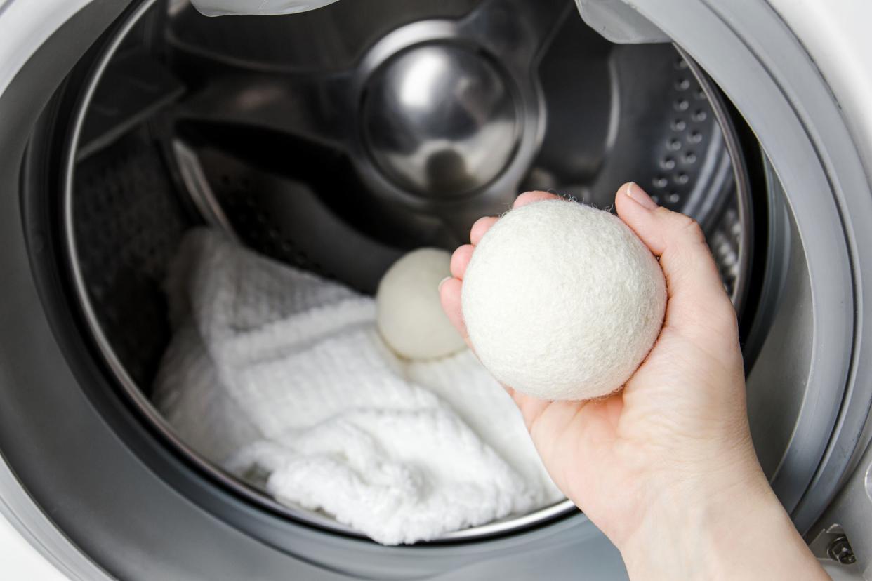 Woman using wool dryer balls to make clothes softer while tumble drying in a washing machine concept. Discharge static electricity and shorten drying time, save energy.