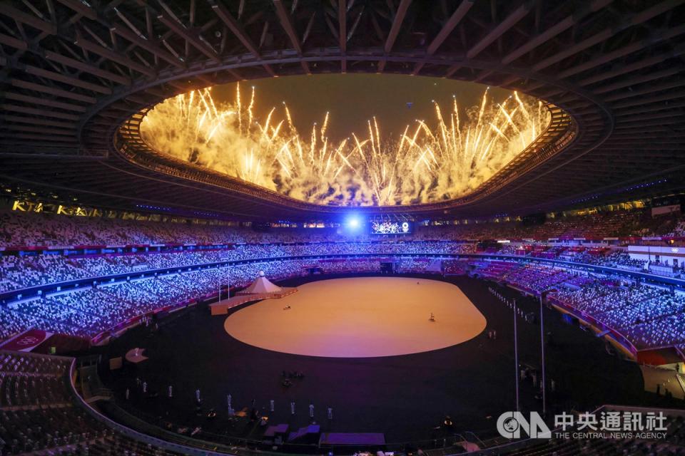 東京奧運23日晚間在日本新宿國立競技場舉行開幕式，受疫情影響本屆典禮並未開放觀眾進入場內，但現場表演仍照常舉行，璀璨煙火自場館高處噴發，點亮夜空。中央社記者吳家昇攝