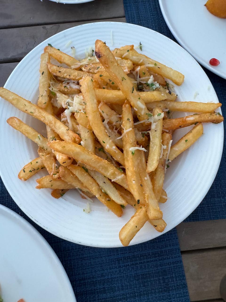 A plate of seasoned French fries served on a table, indicative of local cuisine for travelers