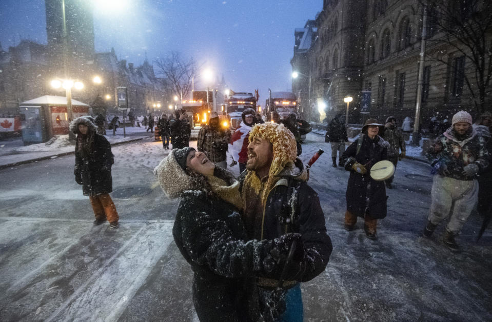 Protesters dance and embrace as a song plays over the speakers, during an ongoing protest against COVID-19 measures that has grown into a broader anti-government protest, in Ottawa, Ontario, on Thursday, Feb. 17, 2022. (Justin Tang/The Canadian Press via AP)