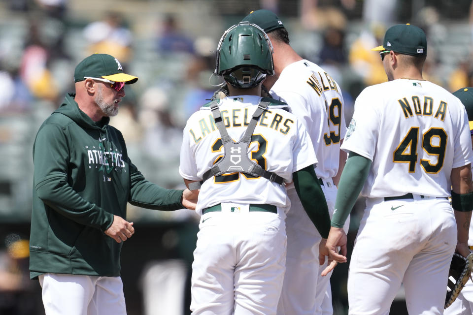 Oakland Athletics manager Mark Kotsay, left, takes the ball from pitcher Kyle Muller, middle, as catcher Shea Langeliers (23) and first baseman Ryan Noda (49) watch during the sixth inning of a baseball game against the Cleveland Guardians in Oakland, Calif., Wednesday, April 5, 2023. (AP Photo/Jeff Chiu)