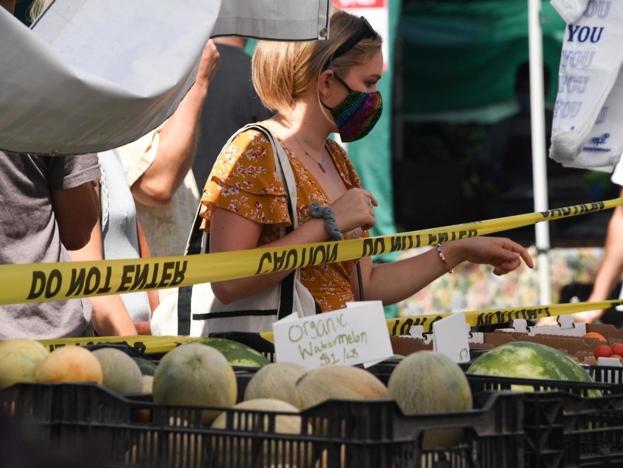 A woman wearing a face covering shops for melons at the Santa Monica Farmers' Market in California: (2020 Getty Images)