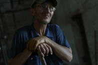 Oleksandr Piatachenko pauses for a moment from sweeping hay at the KramAgroSvit dairy farm in Dmytrivka, Donetsk region, eastern Ukraine, Wednesday, Aug. 10, 2022. "If there were no farming, there would be no work. There isn't any public transport or buses around. You just can't go and find a new job even if you want to," said Piatachenko. (AP Photo/David Goldman)