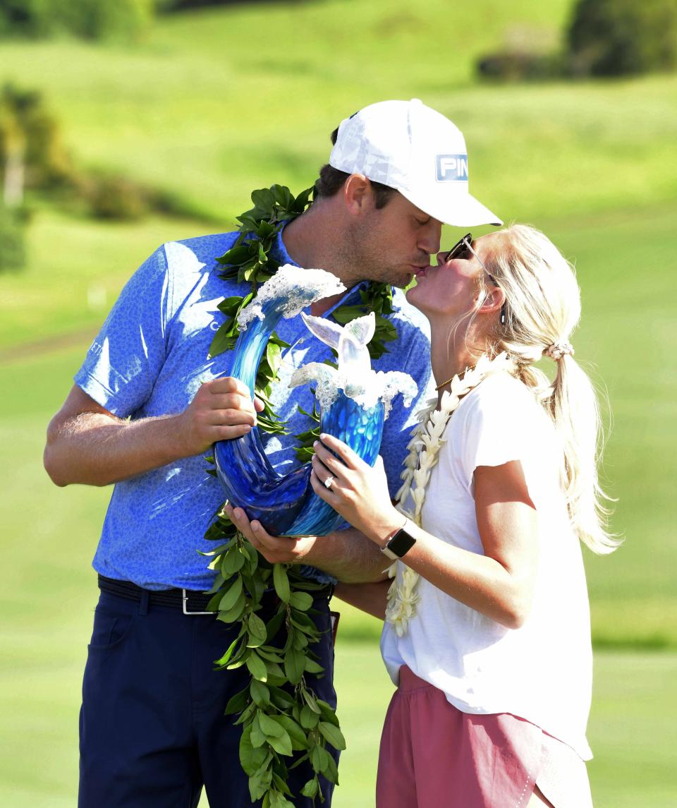 Harris English kisses his wife, Helen English, as he holds the champions trophy after the final round of the Tournament of Champions golf event, Sunday, Jan. 10, 2021, at Kapalua Plantation Course in Kapalua, Hawaii. (Matthew Thayer/The Maui News via AP)