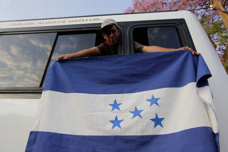 A Honduran migrant, part of a caravan moving through Mexico, holds a Honduras' national flag through a window of a bus bound to Mexico City, in Puebla, Mexico April 9, 2018. REUTERS/Imelda Medina