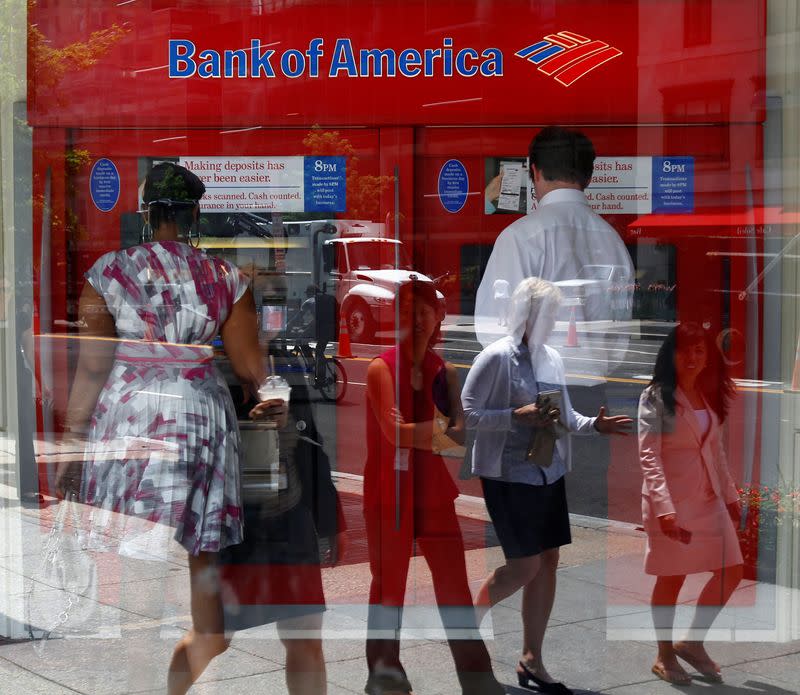 FILE PHOTO: Pedestrians are reflected in the window as customers conduct transactions at a Bank of America ATM in Washington