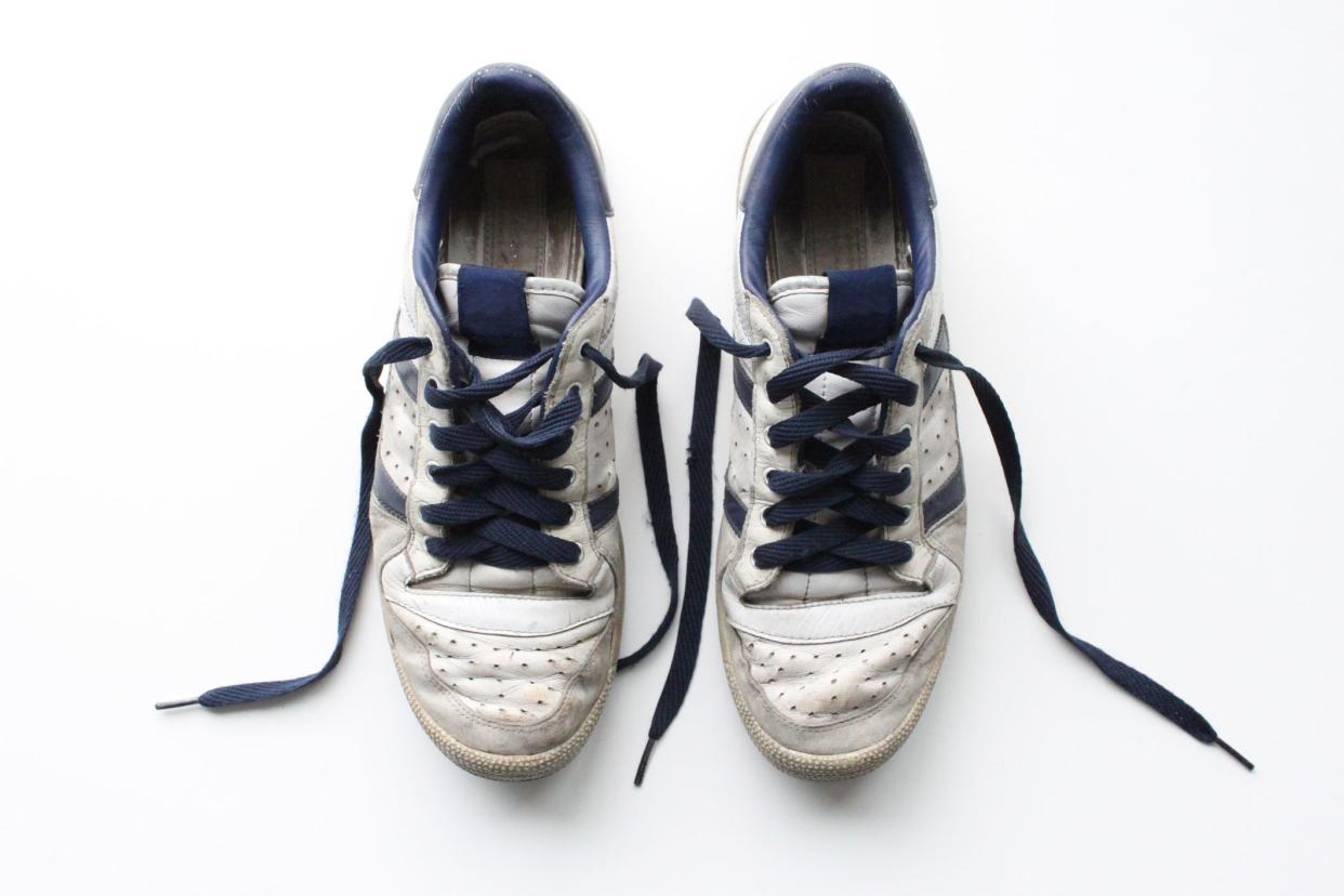 Clean, isolated shot of a pair of old sports shoes, in heavily worn condition.