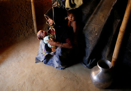 Marijaan, 20, holds her 25-day-old daughter Noor Habi as her son stands inside their shelter in Kutupalang unregistered refugee camp in Cox’s Bazar, Bangladesh, February 9, 2017. REUTERS/Mohammad Ponir Hossain