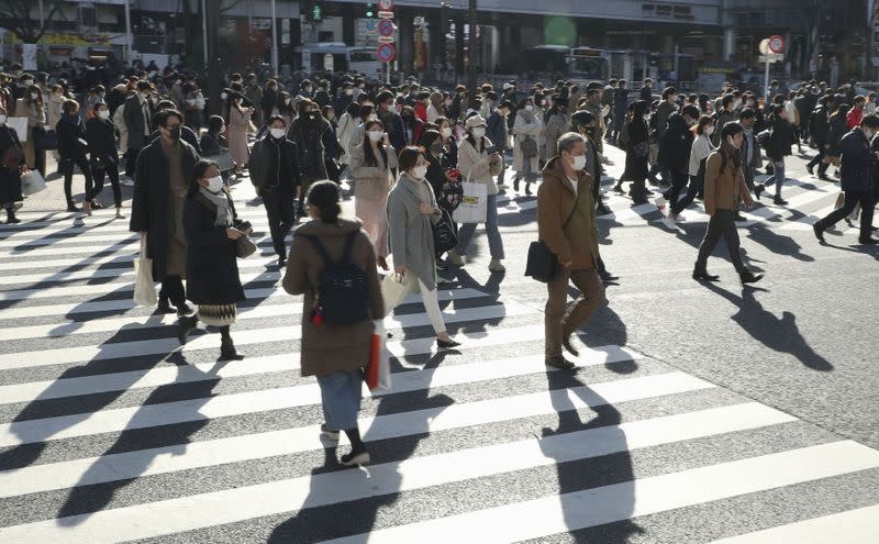 Passersby wearing protective face masks walk on the Shibuya crossing in Tokyo