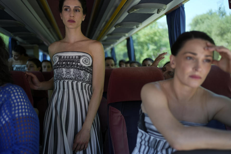 Performers, who will take part in the flame lighting ceremony for the Paris Olympics, sit on a bus after a rehearsal at Ancient Olympia site, Greece, Sunday, April 14, 2024. Every two years, a countdown to the Olympic games is launched from its ancient birthplace with a flame lighting ceremony in southern Greece at Ancient Olympia. The event is marked with a performance by dancers who assume the role of priestesses and male companions, their movement inspired by scenes on millennia-old artwork. (AP Photo/Thanassis Stavrakis)