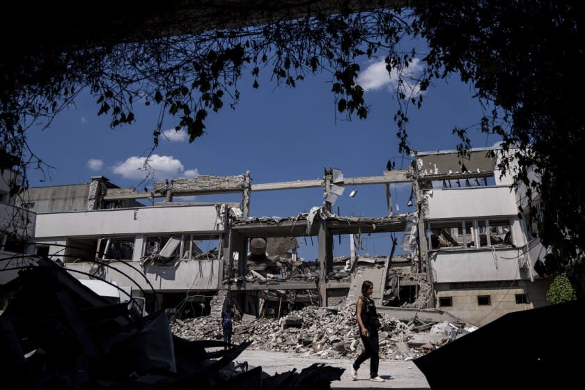 Ukrainian journalists walk in the yard of National Pedagogic university destroyed by a Russian attack in Kharkiv, Ukraine, Wednesday, July 6, 2022. (AP Photo/Evgeniy Maloletka)