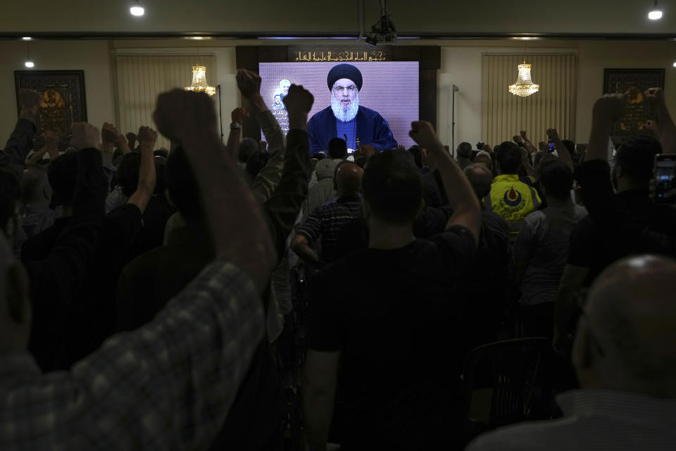 Hezbollah supporters raise their fists and cheer as they watch a speech given by Hezbollah leader Sayyed Hassan Nasrallah on a screen during a ceremony to commemorate the death of senior Hezbollah commander Taleb Sami Abdullah, 55, who was killed last week by an Israeli strike in south Lebanon, in the southern Beirut suburb of Dahiyeh, Lebanon, Wednesday, June 19, 2024. (AP Photo/Bilal Hussein)