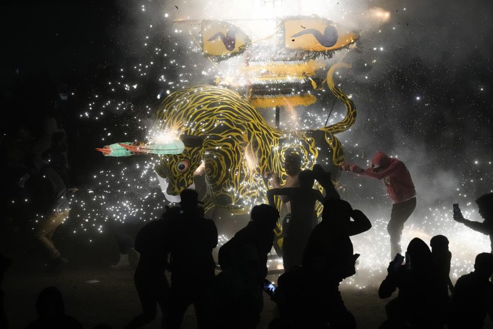 People dance around a giant paper-mache bull stuffed with fireworks as roman candles and bottle rockets shower them with sparks, during the annual festival honoring Saint John of God, in Tultepec, Mexico, Friday, March 8, 2024. The celebration, now its 35th year, pays homage to the patron saint of the poor and sick, St. John of God, who the fireworks' producers view as a protective figure. (AP Photo/Marco Ugarte)